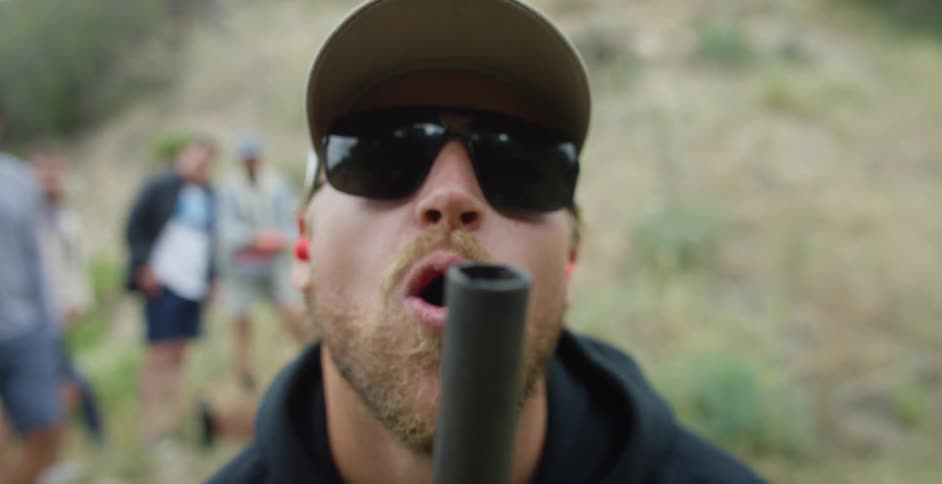 A man pretends to out a smoking pipe and laughs as friends standing behind him watch