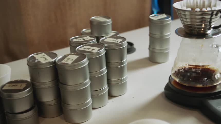 A glass coffee pot that is collecting drip coffee has a filter atop that is filled with ground coffee