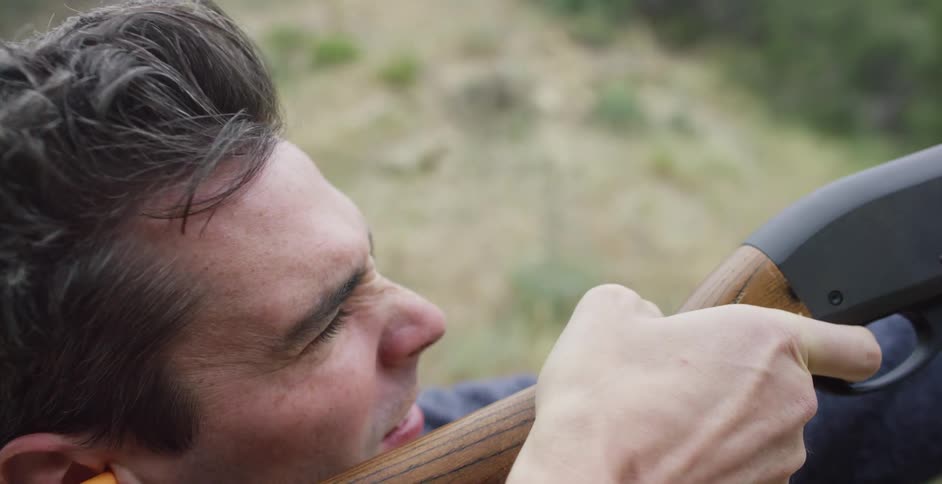 A man on a hill shoots a rifle