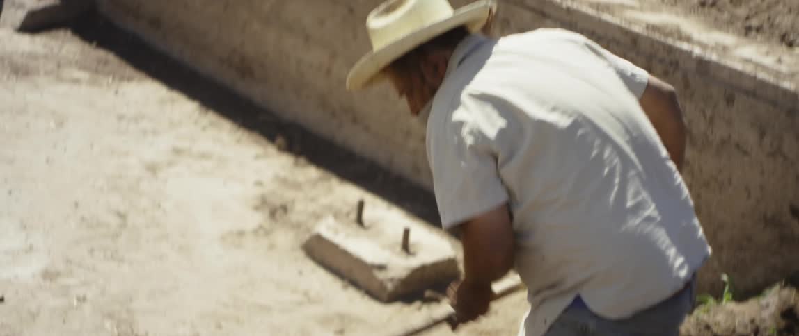 A man in digs in the soil using an entrenching tool