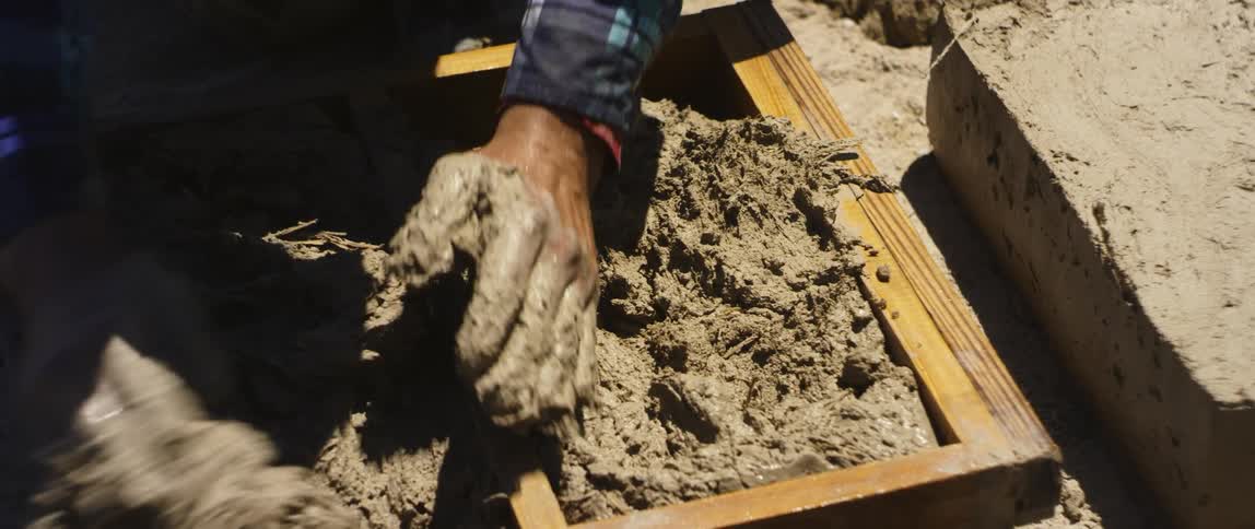 A person packing clay into wooden boxes