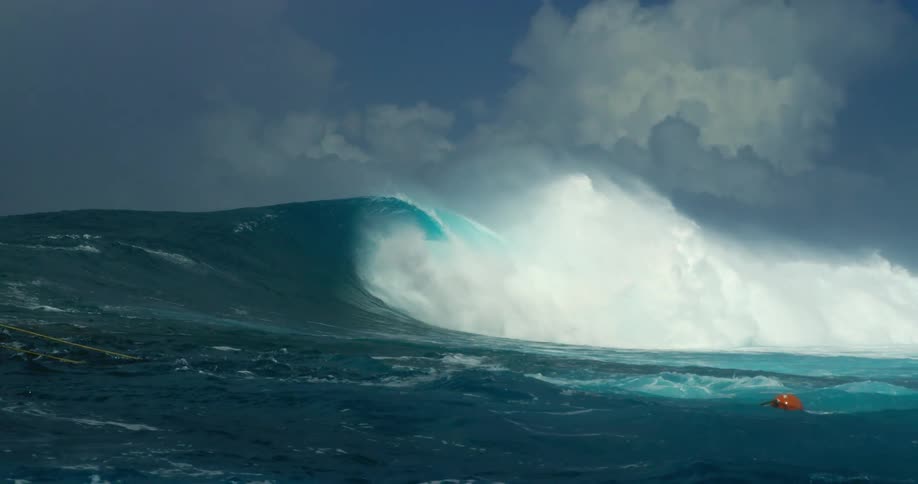 Large wave in the ocean as someone clings to ropes in the water
