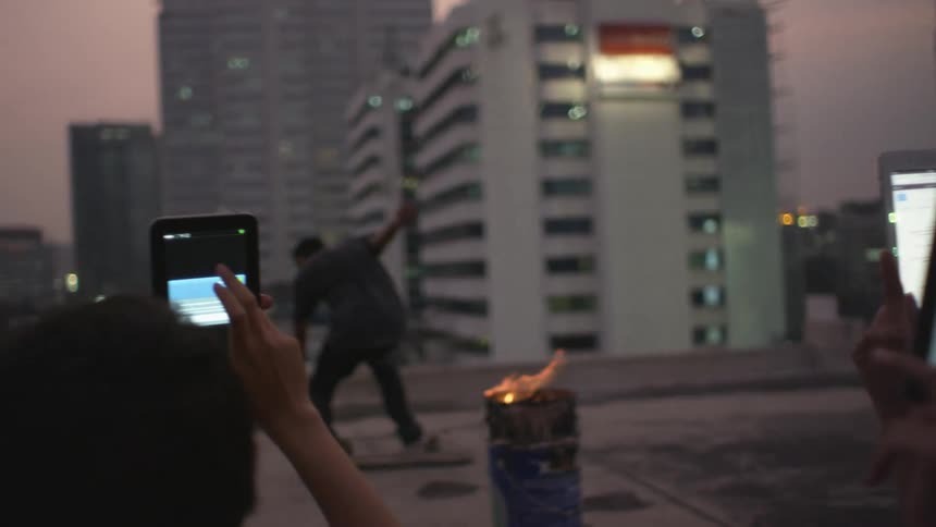 People record a man jumping on a roof with a skateboard