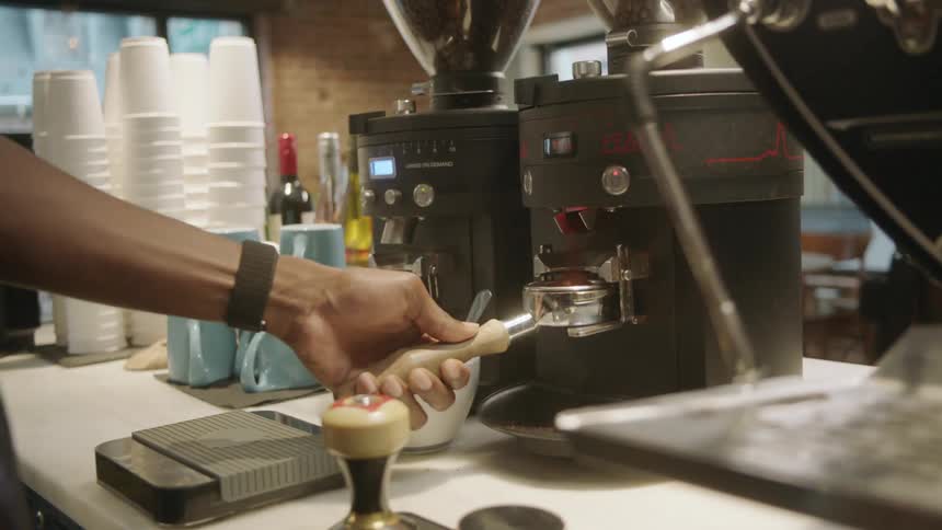 An employee at a coffee shop putting coffee in a machine