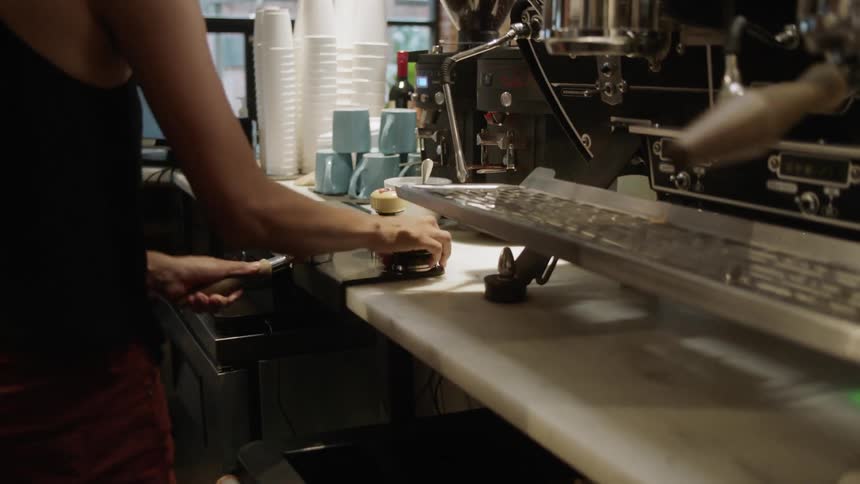 A barista presses the coffee grounds into an espresso filter