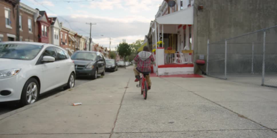 A boy is riding his bike down a sidewalk