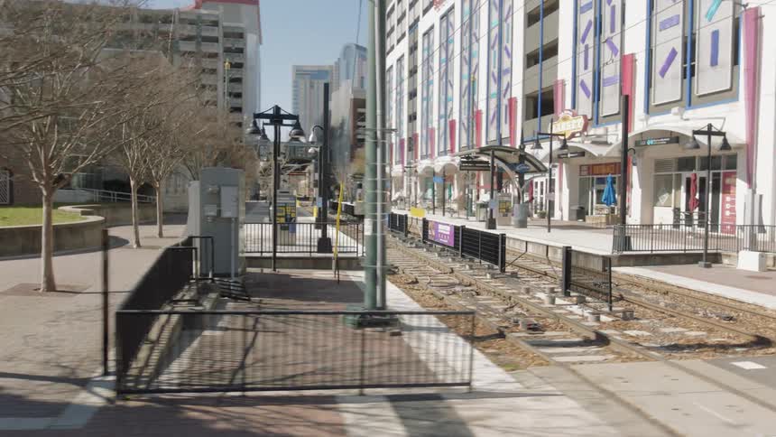 In the middle of a city filled with several tall buildings is a set of commuter railway tracks