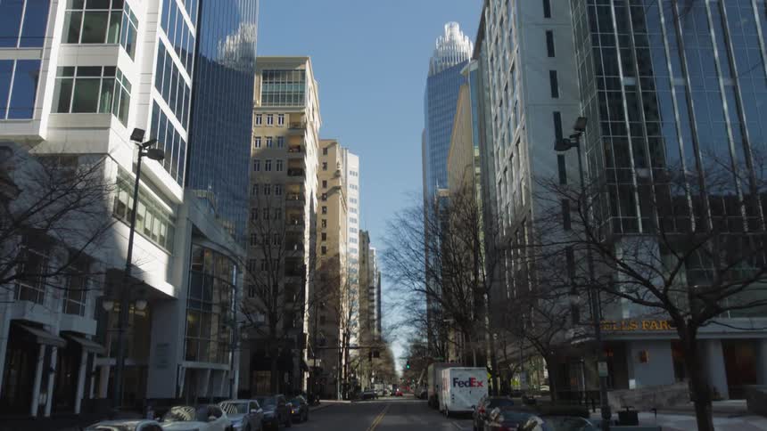 A street lined with vehicles and tall buildings in a metropolis on a clear day