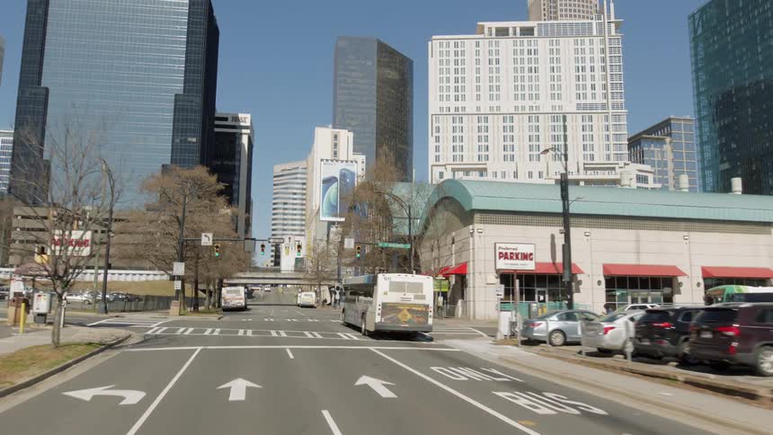 City bus drives through intersection turning toward bus transit station near downtown tower blocks