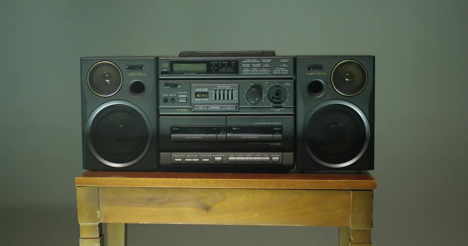 A boom box radio is sitting on a table as lights and shadows move across the room