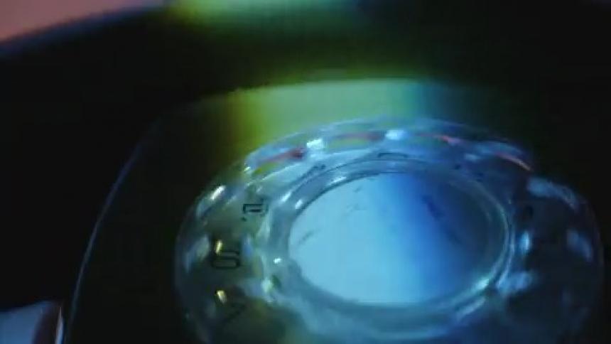 A person uses their finger to dial some numbers on an older rotary dial phone