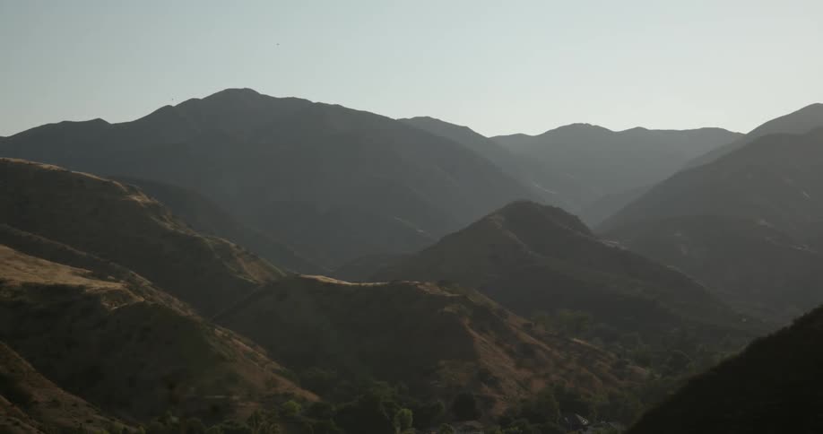 Mountains and a mountain range in the distance under a hazy sky
