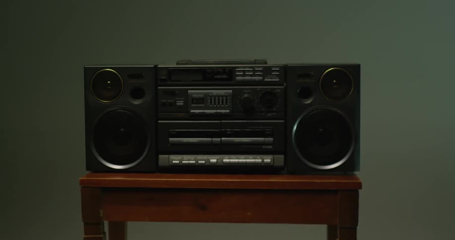 A boom box radio is sitting on a table as lights and shadows move across the room