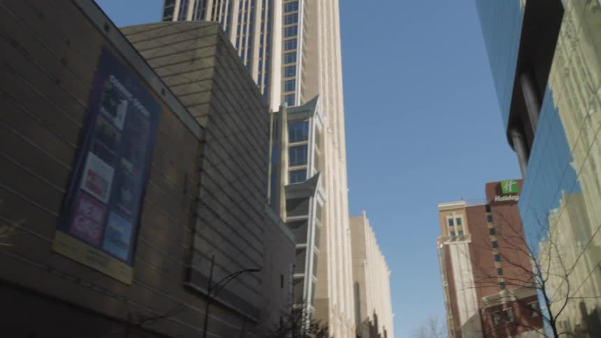 Cars drive past office buildings and businesses in a downtown area