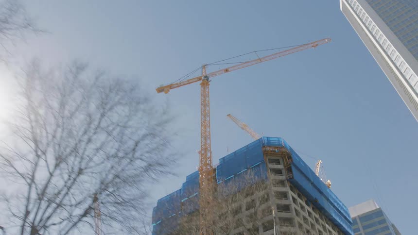 A construction crane sits next to a high rise office building in a city