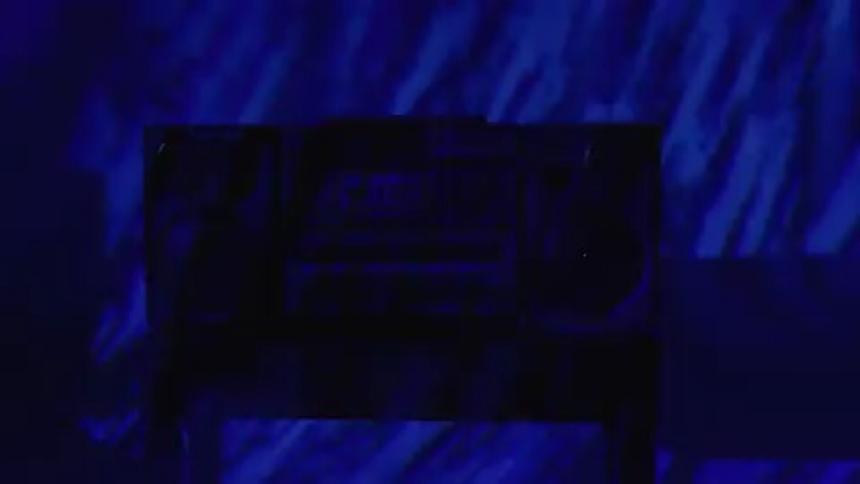 Bright blue strobe lights flash around a table with a boom box on it