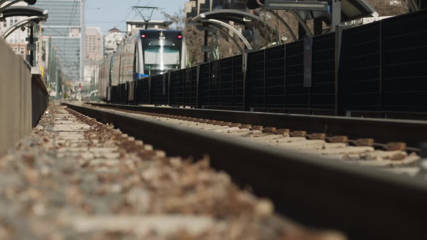 Trolley car travels next to a fence in the city