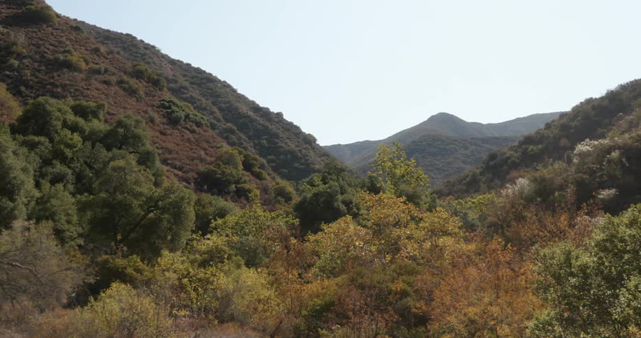 A landscape with hills and trees with the sky and clouds in the background