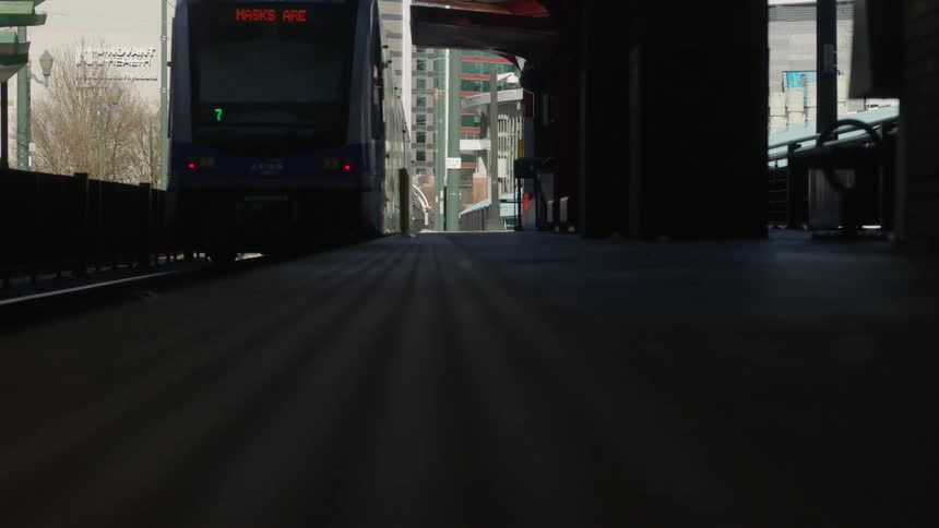 A train pulls out of a train station in a city during the day