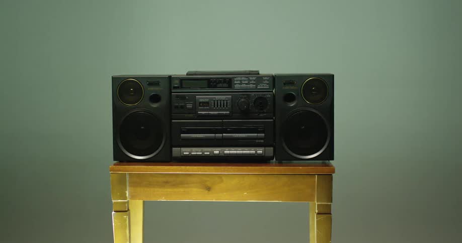 A boom box radio is sitting on a table as lights and shadows move across the room