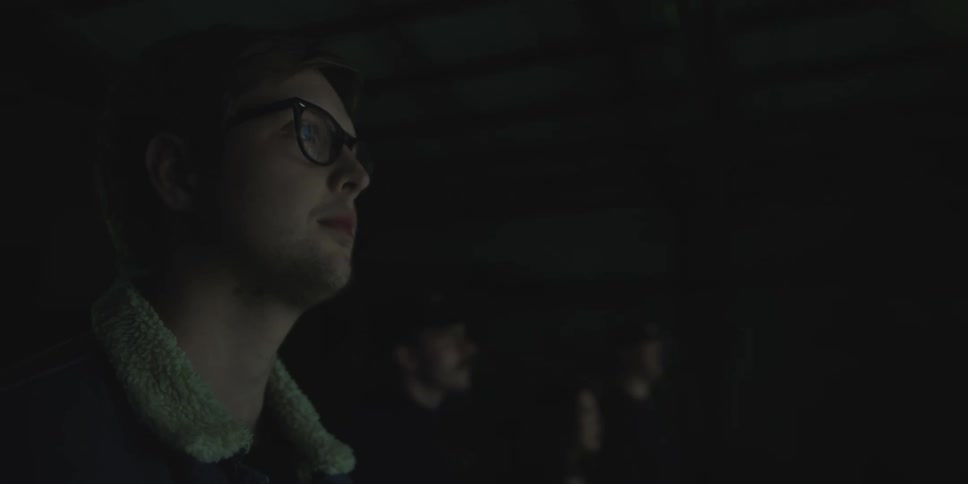 A young man stands while attentively watching an illuminated display in front of him