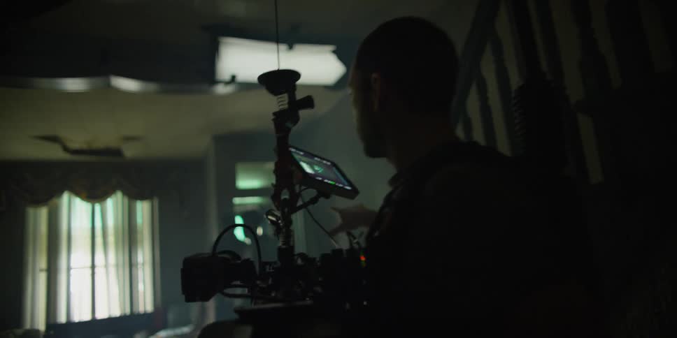 A man holds a camera walking in a home