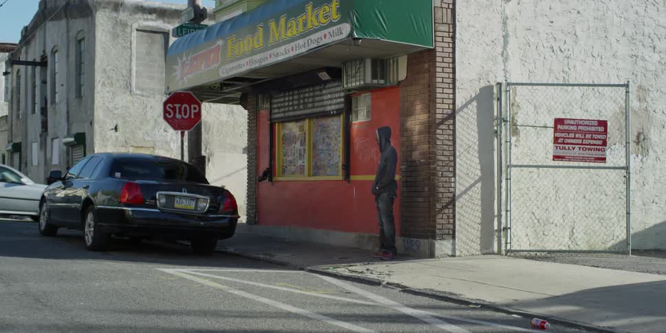 A man stands near a store on a street corner