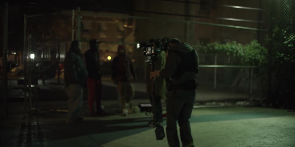 A man walks while filming towards a group of people and they run off