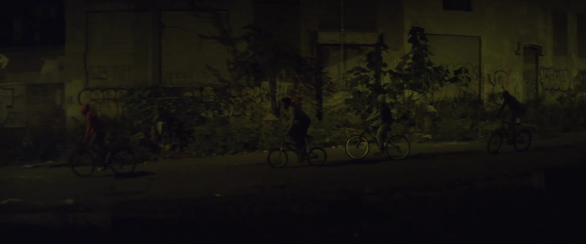 Boys riding bicycles near an abandoned building in a run-down industrial area