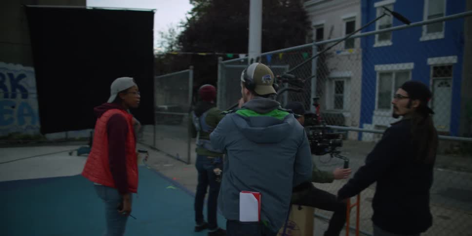 A group of people filming through a fence