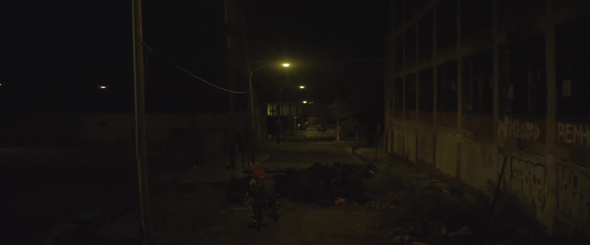 Boys riding their bicycles through an industrial area at night