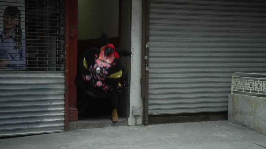Dancer performs dance wearing animal costume and standing in doorway of business