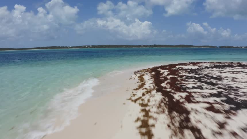 A beach with sand with the ocean sky and clouds in the background