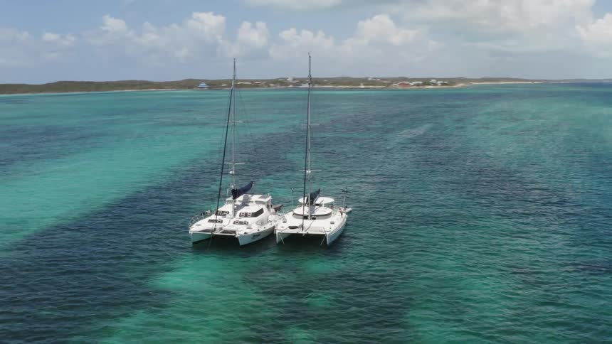 An aerial view of two sailboats on the ocean
