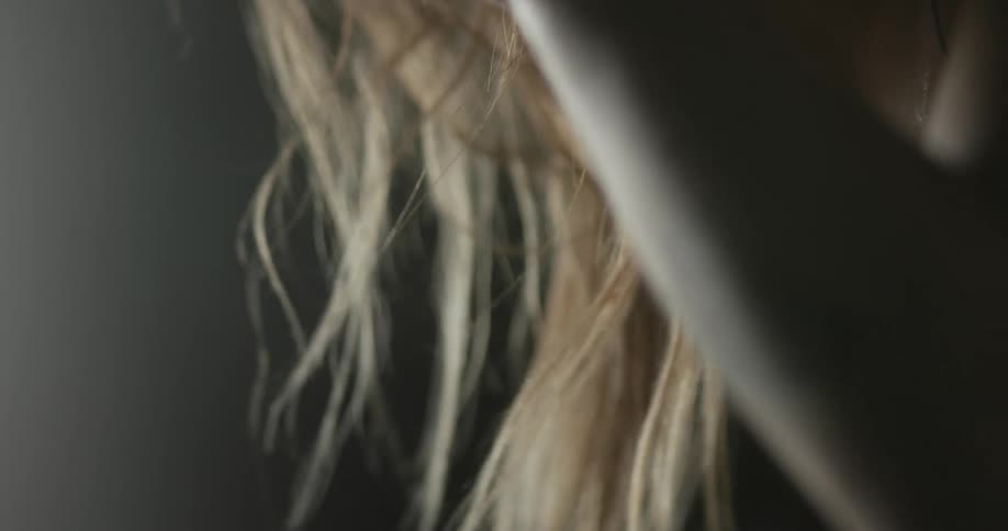 A woman with long blonde hair blowing in the breeze lifts her arm