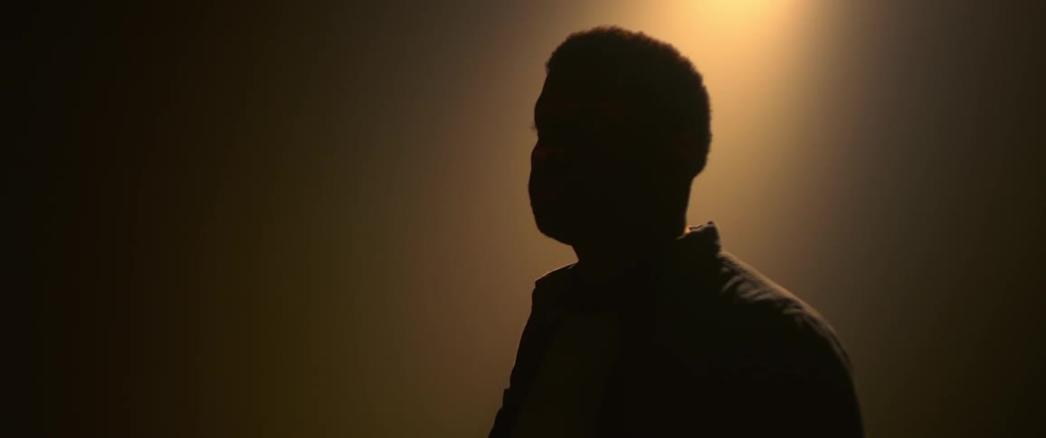 The silhouette man standing in a dimly lit room