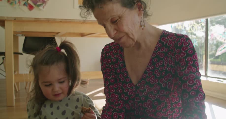 A grandmother putting shoes on her granddaughter
