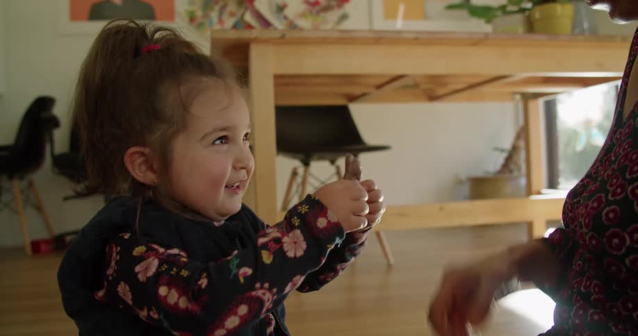 A woman gives a child a piece of chocolate