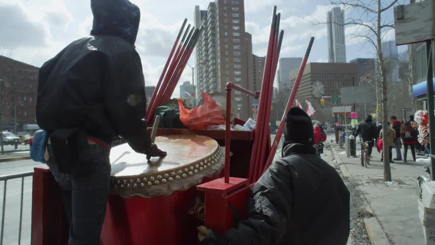 A wagon with a man playing drums moves past the pedestrians