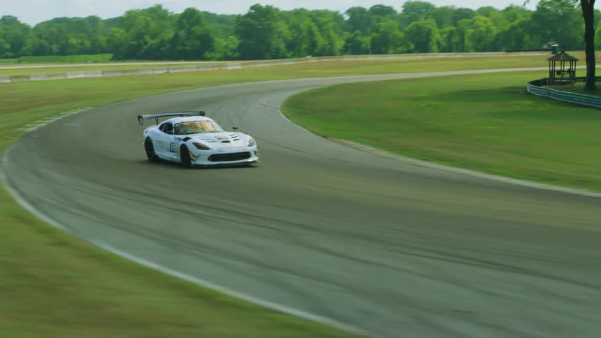 Cars race on a racetrack with trees in the distance