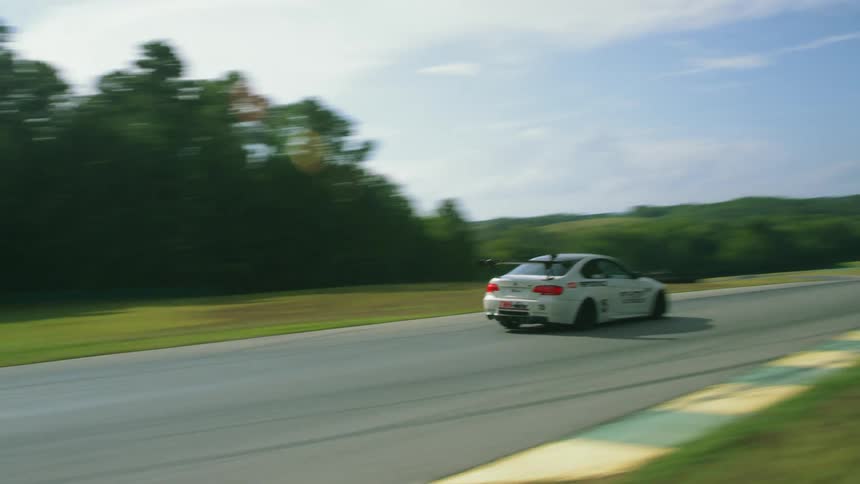 A race car speeds by the long road