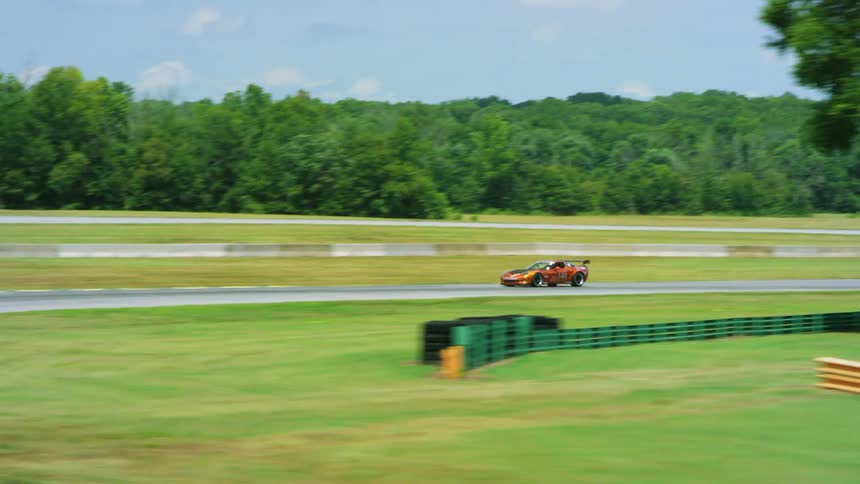 Race cars speed along race track through curves