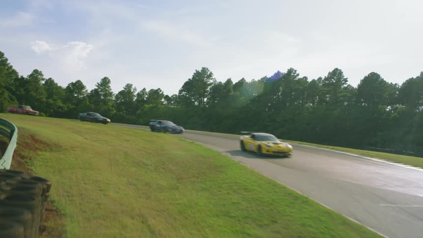 Racing cars in single file on a race track near the trees
