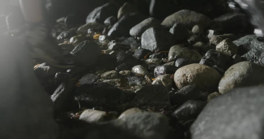 Man and woman walk over the rocks in a stream