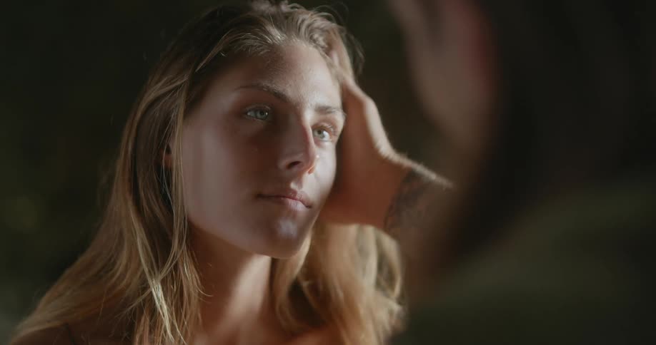 Couple look into each others faces and stroke hands through each others hair