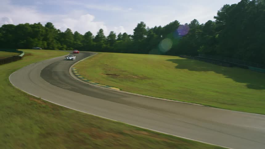 Aerial view of colorful race cars running on a race track at daytime