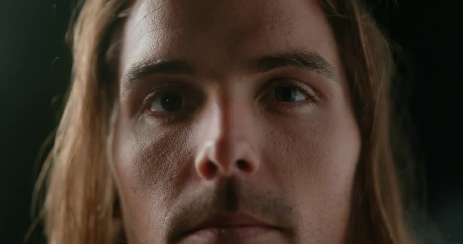 A man with long hair and a mustache looks straight ahead