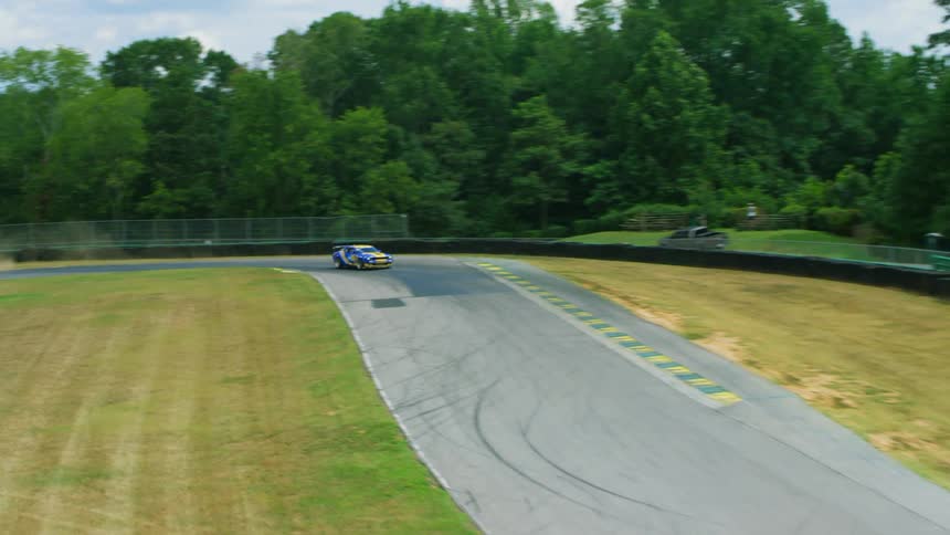 A blue and yellow race car drives on a track