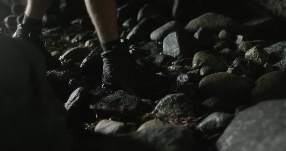 Two people walk across wet rocks in the night