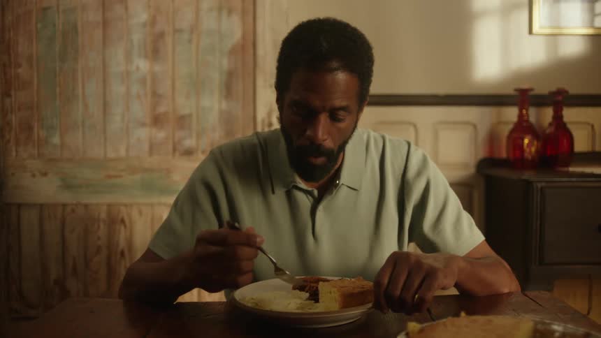 A man sits at a table eating a meal in his home alone